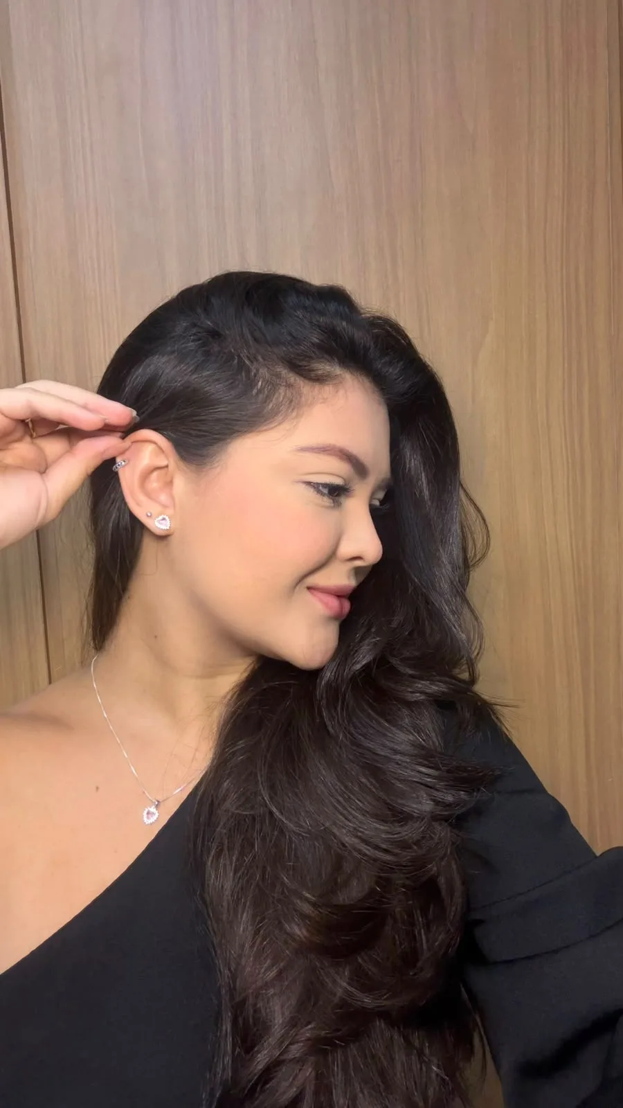 Modelo de perfil, de cabelo solto, usando brinco e colar fino em prata 925